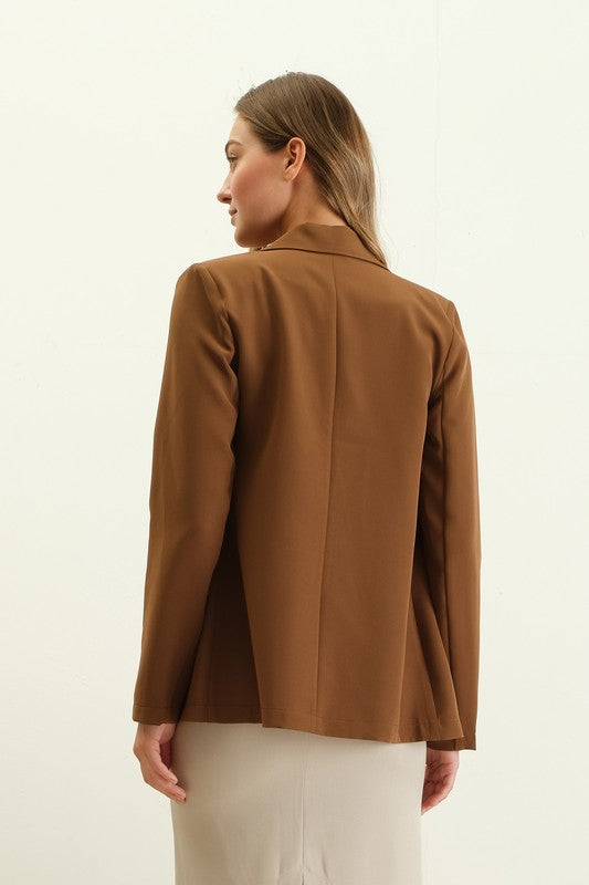 Woman wearing a brown shoulder pad double-breasted blazer with a structured, elegant fit.