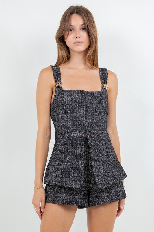 Woman wearing a tweed corset top and matching mini shorts with metal trim, styled for a modern elegant look.