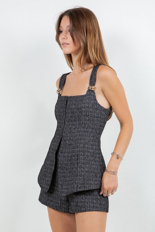 Woman wearing a tweed corset top and matching mini shorts with metal trim, styled for a modern elegant look.