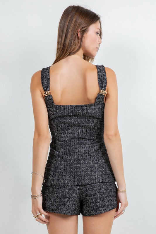 Woman wearing a tweed corset top and matching mini shorts with metal trim, styled for a modern elegant look.