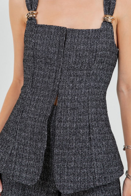 Woman wearing a tweed corset top and matching mini shorts with metal trim, styled for a modern elegant look.