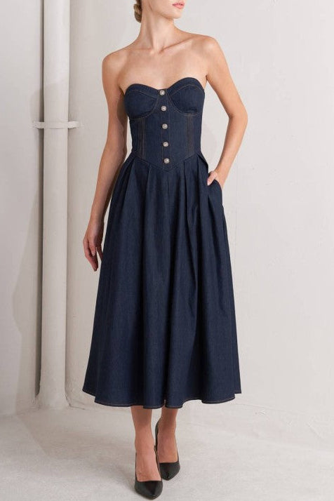 Woman wearing a strapless denim midi dress with a sweetheart neckline, structured bustier bodice, basque waist, and full skirt.