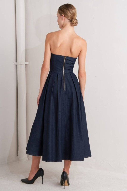 Woman wearing a strapless denim midi dress with a sweetheart neckline, structured bustier bodice, basque waist, and full skirt.