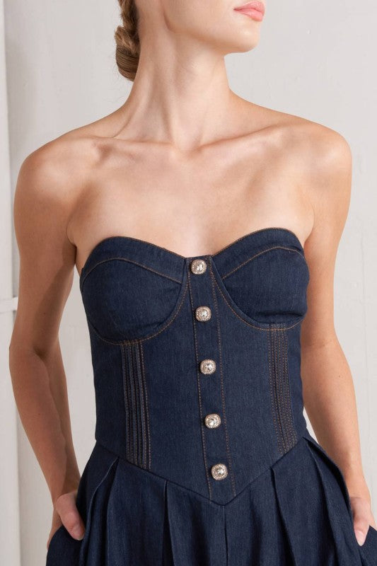 Woman wearing a strapless denim midi dress with a sweetheart neckline, structured bustier bodice, basque waist, and full skirt.