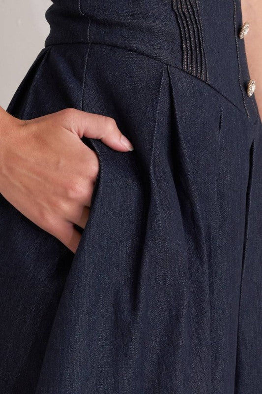 Woman wearing a strapless denim midi dress with a sweetheart neckline, structured bustier bodice, basque waist, and full skirt.