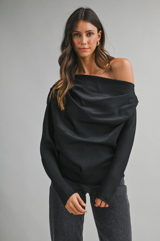 Woman wearing a one-shoulder draped top with an elegant asymmetrical neckline and flowing fabric, styled for a chic day-to-night look.