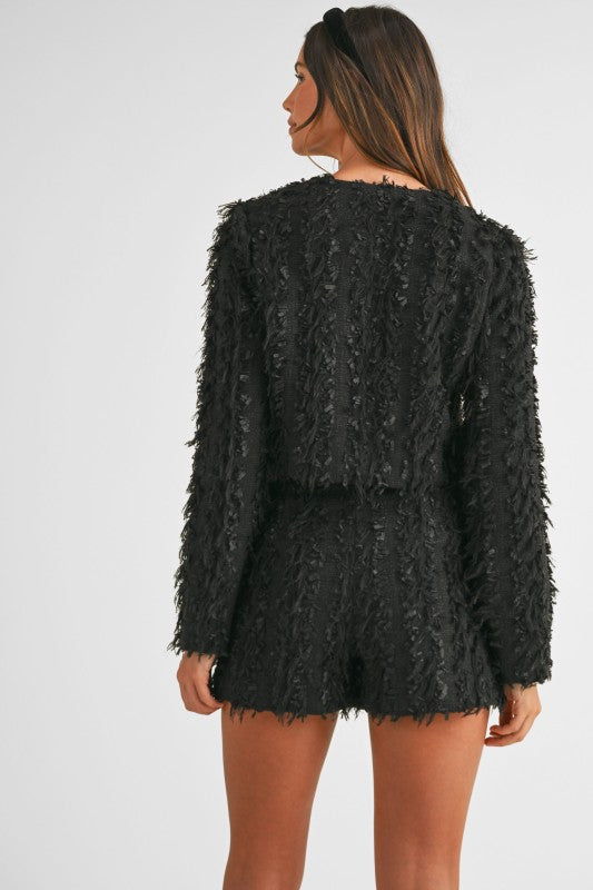 Woman wearing a coordinated tweed jacket and skirt set styled for an elegant, polished office-to-evening look.