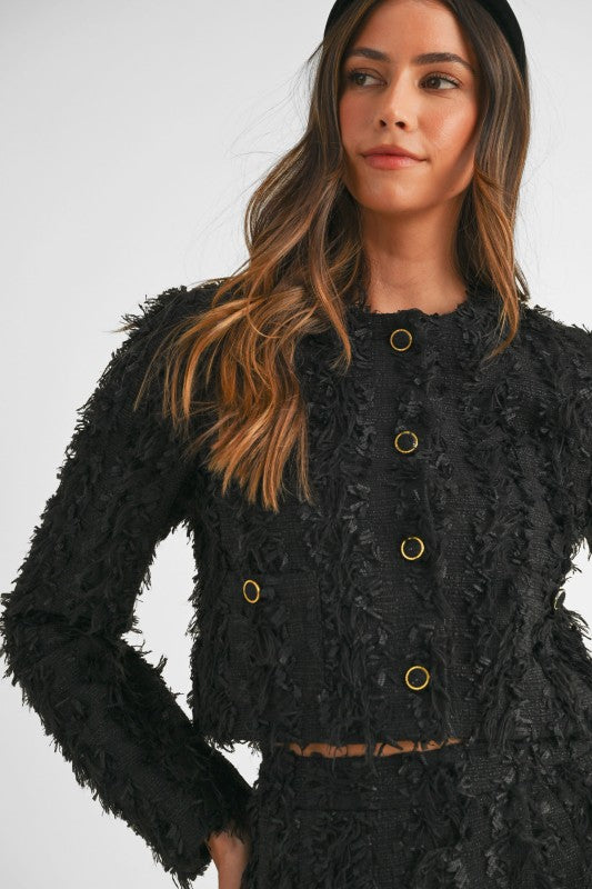 Woman wearing a coordinated tweed jacket and skirt set styled for an elegant, polished office-to-evening look.