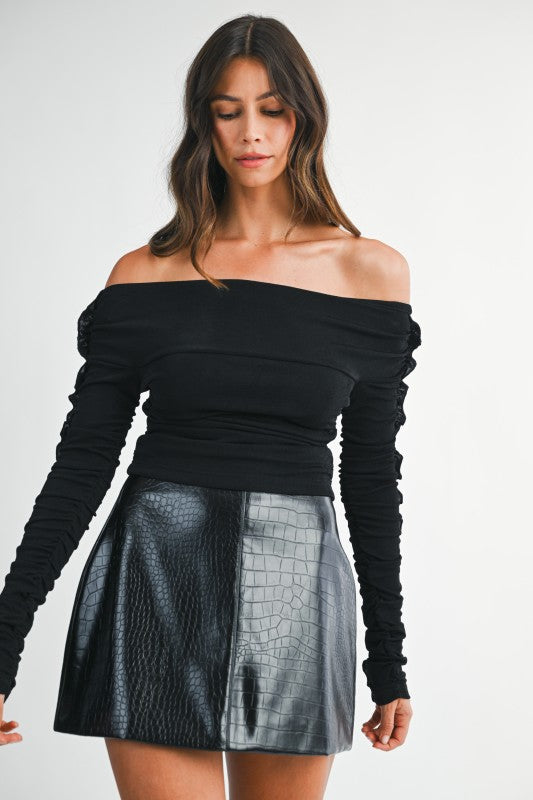 Woman wearing an off-shoulder knit Bardot top styled for an effortlessly chic and flattering day-to-night look.