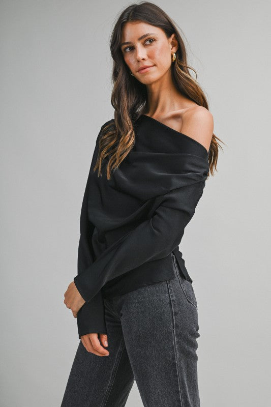 Woman wearing a one-shoulder draped top with an elegant asymmetrical neckline and flowing fabric, styled for a chic day-to-night look.
