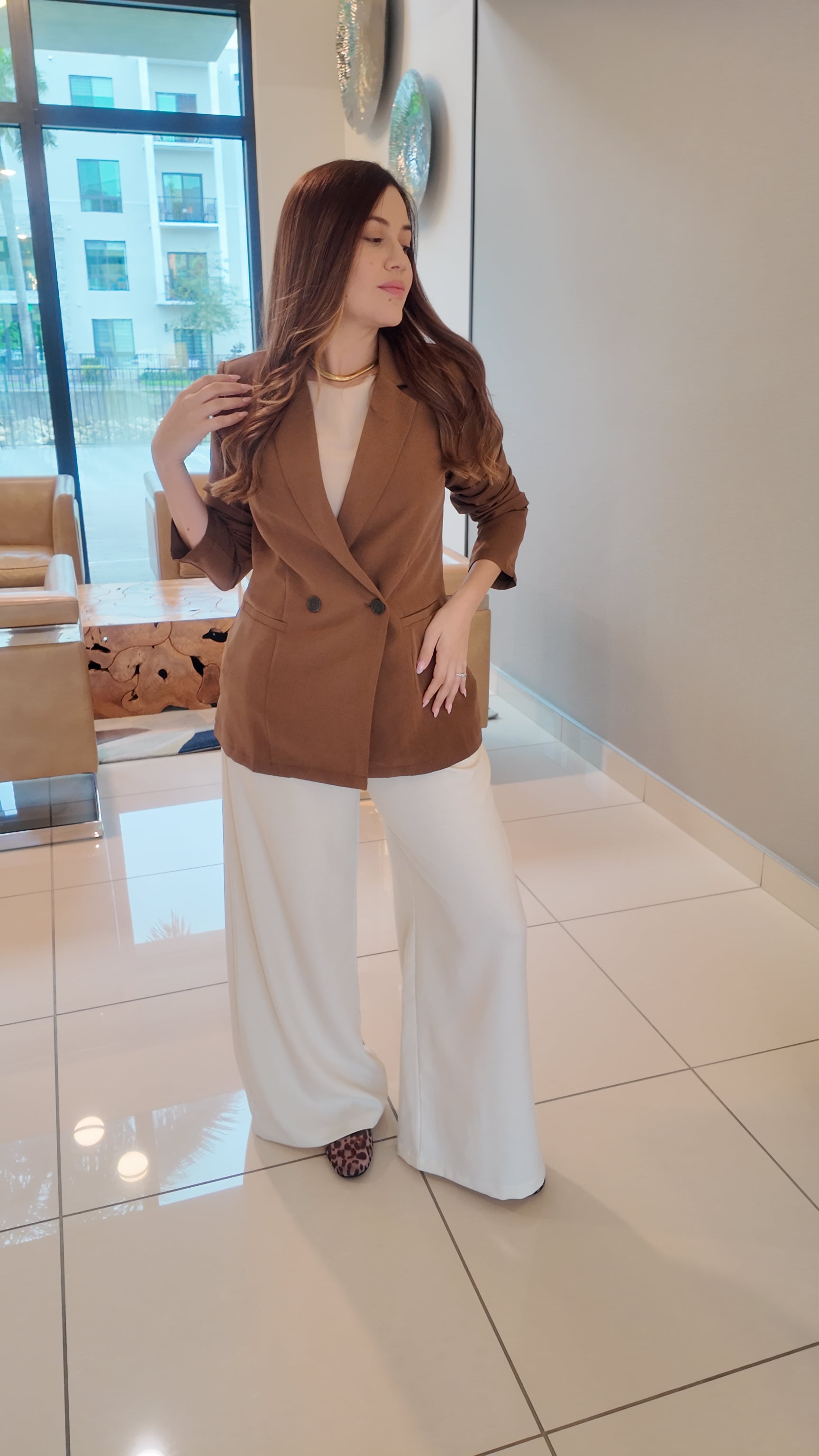 Woman wearing a brown shoulder pad double-breasted blazer with a structured, elegant fit.