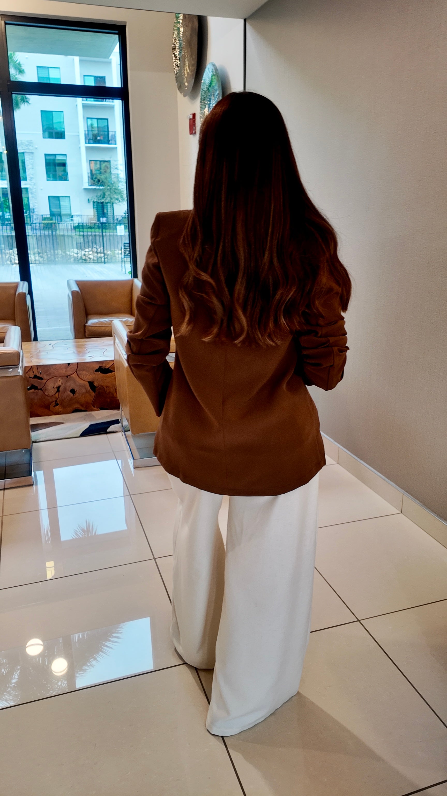 Woman wearing a brown shoulder pad double-breasted blazer with a structured, elegant fit.