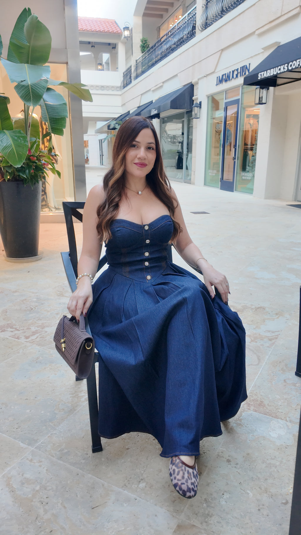 Woman wearing a strapless denim midi dress with a sweetheart neckline, structured bustier bodice, basque waist, and full skirt.